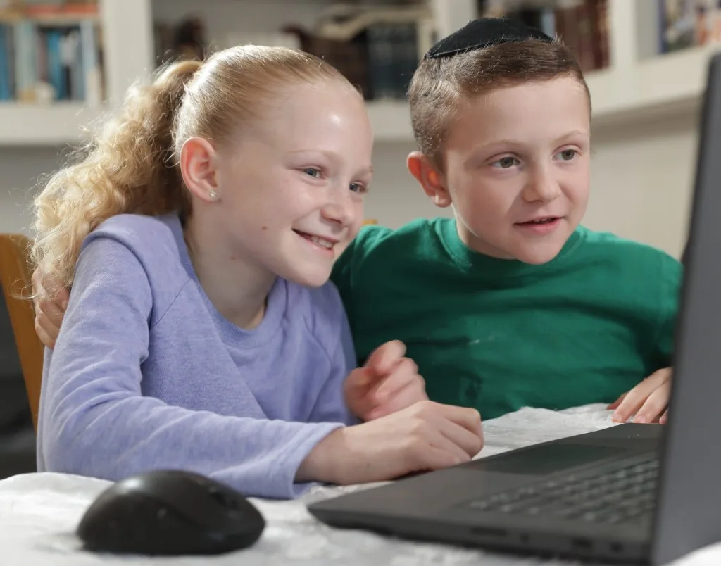 A girl and boy watching a Torah Live video together
